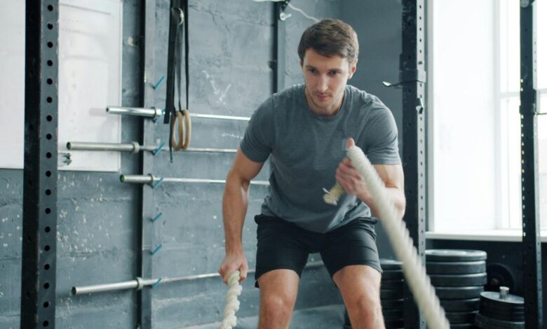 Man using battle ropes during workout in gym