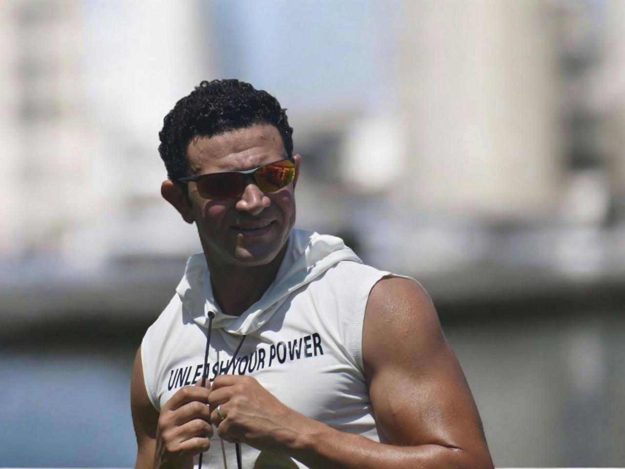 Man wearing sunglasses and a sleeveless hoodie outdoors